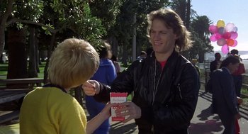 Movie still from “Xanadu” (1980), directed by Robert Greenwald – A young man is handing a book to a young woman; Medium shot, Over the shoulder angle
