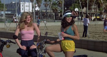 Movie still from “Xanadu” (1980), directed by Robert Greenwald – Two young women standing next to each other on a bike; Wide shot, High angle