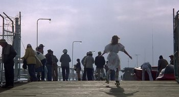 Movie still from “Xanadu” (1980), directed by Robert Greenwald – A group of people standing on top of a wooden pier; Wide shot, Low angle