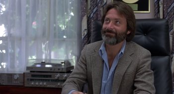 Movie still from “Xanadu” (1980), directed by Robert Greenwald – A man sitting in a chair in front of a window; Close Up shot, Low angle