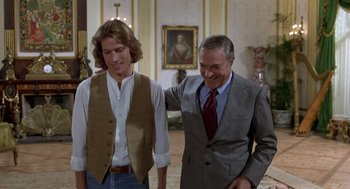 Movie still from “Xanadu” (1980), directed by Robert Greenwald – A man in a suit and tie standing next to another man; Medium shot, Over the shoulder angle