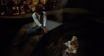 Movie still from “Xanadu” (1980), directed by Robert Greenwald – A man and a woman are sitting on a wall; Wide shot, High angle