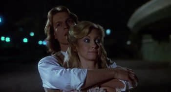 Movie still from “Xanadu” (1980), directed by Robert Greenwald – A man and a woman standing next to each other in front of lights; Close Up shot, Low angle