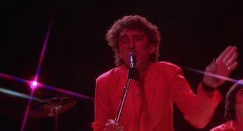 Movie still from “Xanadu” (1980), directed by Robert Greenwald – A man in a red shirt singing into a microphone; Close Up shot, Low angle