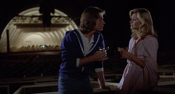 Movie still from “Xanadu” (1980), directed by Robert Greenwald – Two women standing next to each other holding drinks; Medium shot, Low angle