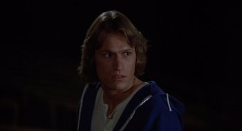 Movie still from “Xanadu” (1980), directed by Robert Greenwald – A man with long brown hair wearing a blue hooded sweatshirt; Close Up shot, Over the shoulder angle
