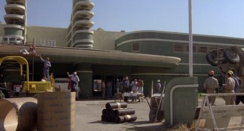 Movie still from “Xanadu” (1980), directed by Robert Greenwald – A group of people standing outside of a building; Extreme Wide shot, Low angle