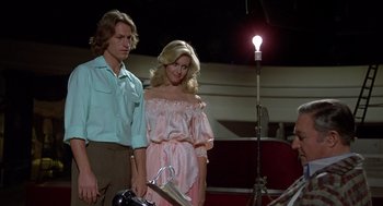 Movie still from “Xanadu” (1980), directed by Robert Greenwald – A man standing next to a woman in front of a light; Medium shot, Low angle
