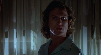 Movie still from “Xanadu” (1980), directed by Robert Greenwald – A man with long brown hair is standing in front of a window; Close Up shot, Low angle
