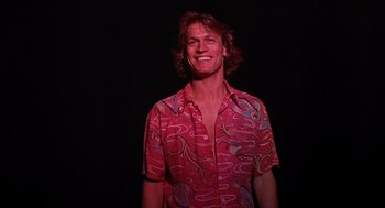 Movie still from “Xanadu” (1980), directed by Robert Greenwald – A man in a red shirt smiling for the camera; Close Up shot, Low angle