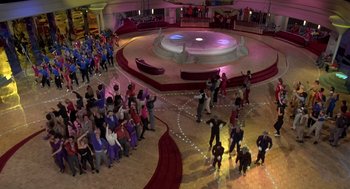 Movie still from “Xanadu” (1980), directed by Robert Greenwald – A group of people standing in a large room; Extreme Wide shot, High angle