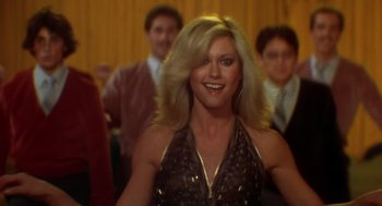 Movie still from “Xanadu” (1980), directed by Robert Greenwald – A woman with long blonde hair in a brown dress; Close Up shot, Low angle