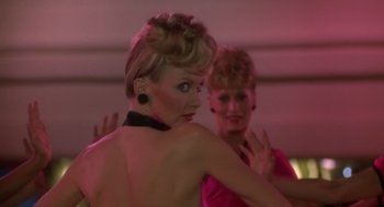 Movie still from “Xanadu” (1980), directed by Robert Greenwald – A woman in a pink dress is reflected in a mirror; Close Up shot, Over the shoulder angle