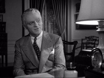 Movie still from “Yankee Doodle Dandy” (1942), directed by Michael Curtiz – An older man sitting at a table in front of a lamp; Medium shot, Low angle