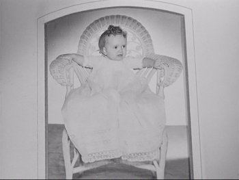 Movie still from “Yankee Doodle Dandy” (1942), directed by Michael Curtiz – An old black and white photo of a little girl sitting in a rocking chair; Medium shot, High angle