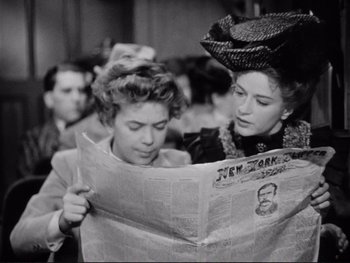 Movie still from “Yankee Doodle Dandy” (1942), directed by Michael Curtiz – Two women are reading a newspaper in a crowded room; Close Up shot, Low angle