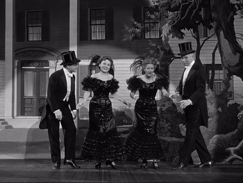 Movie still from “Yankee Doodle Dandy” (1942), directed by Michael Curtiz – A black and white photo of two men and two women in formal wear; Wide shot, High angle
