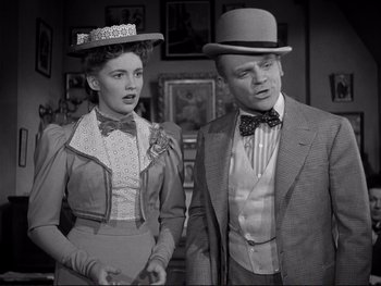 Movie still from “Yankee Doodle Dandy” (1942), directed by Michael Curtiz – A man and a woman wearing hats standing next to each other; Medium shot, Low angle