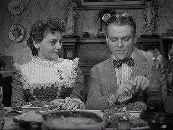 Movie still from “Yankee Doodle Dandy” (1942), directed by Michael Curtiz – A man and a woman sitting at a dinner table; Medium shot, High angle