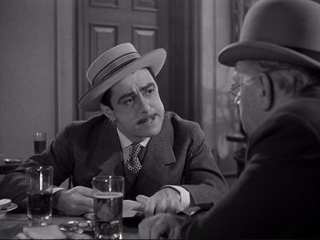 Movie still from “Yankee Doodle Dandy” (1942), directed by Michael Curtiz – Two men sitting at a table talking to each other; Medium shot, Over the shoulder angle