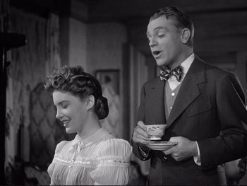Movie still from “Yankee Doodle Dandy” (1942), directed by Michael Curtiz – A man and a woman standing next to each other; Medium shot, Low angle