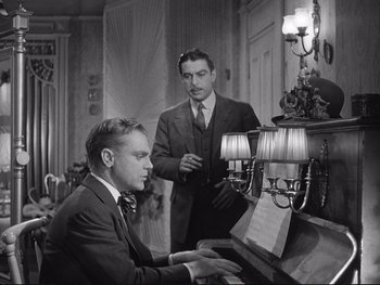 Movie still from “Yankee Doodle Dandy” (1942), directed by Michael Curtiz – Two men in suits are playing piano in a living room; Medium shot, Low angle