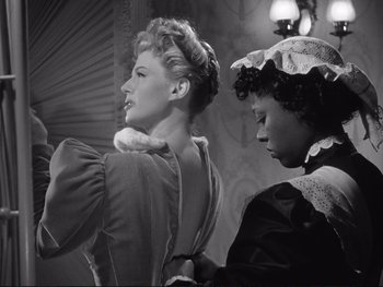 Movie still from “Yankee Doodle Dandy” (1942), directed by Michael Curtiz – Two women dressed in old fashion clothing looking at each other; Medium shot, Low angle