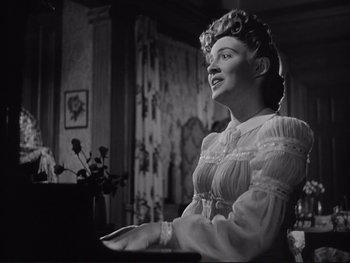 Movie still from “Yankee Doodle Dandy” (1942), directed by Michael Curtiz – An old photo of a woman in an old fashioned dress; Medium shot, Low angle