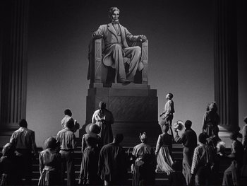Movie still from “Yankee Doodle Dandy” (1942), directed by Michael Curtiz – A group of people standing around a statue of abraham lincoln; Extreme Wide shot, Low angle