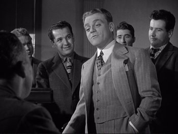 Movie still from “Yankee Doodle Dandy” (1942), directed by Michael Curtiz – A group of men standing around each other in a room; Medium shot, Low angle