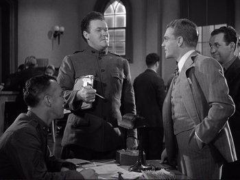 Movie still from “Yankee Doodle Dandy” (1942), directed by Michael Curtiz – A group of men standing next to each other in a room; Medium shot, Low angle