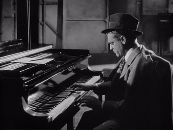 Movie still from “Yankee Doodle Dandy” (1942), directed by Michael Curtiz – A black and white photo of a man playing the piano; Medium shot, High angle