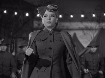 Movie still from “Yankee Doodle Dandy” (1942), directed by Michael Curtiz – A woman in a military uniform standing in front of a group of men; Medium shot, Low angle