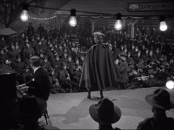 Movie still from “Yankee Doodle Dandy” (1942), directed by Michael Curtiz – An old photo of a woman on a stage in front of an audience; Wide shot, High angle