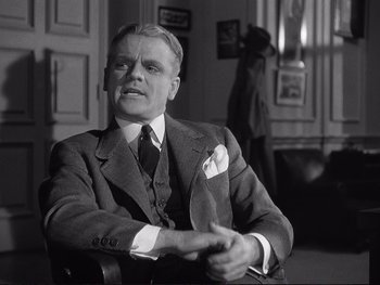 Movie still from “Yankee Doodle Dandy” (1942), directed by Michael Curtiz – An older man sitting in a chair wearing a suit and tie; Medium shot, Low angle