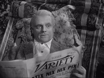 Movie still from “Yankee Doodle Dandy” (1942), directed by Michael Curtiz – An older man sitting in a chair reading a newspaper; Close Up shot, High angle