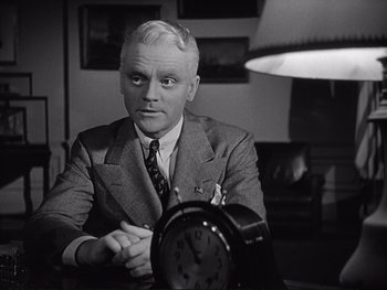 Movie still from “Yankee Doodle Dandy” (1942), directed by Michael Curtiz – A man sitting in front of an alarm clock in a room; Close Up shot, Low angle
