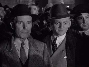 Movie still from “Yankee Doodle Dandy” (1942), directed by Michael Curtiz – A black and white photo of two men in suits and hats; Medium shot, Low angle