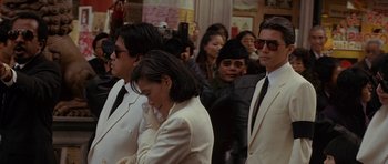 Movie still from “Year of the Dragon” (1985), directed by Michael Cimino – A group of people standing around each other in a crowd; Medium shot, High angle