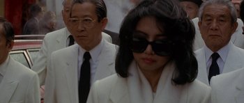 Movie still from “Year of the Dragon” (1985), directed by Michael Cimino – A man and a woman wearing white suits and sunglasses; Close Up shot, High angle