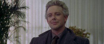 Movie still from “Year of the Dragon” (1985), directed by Michael Cimino – A person wearing a suit and tie; Close Up shot, Over the shoulder angle