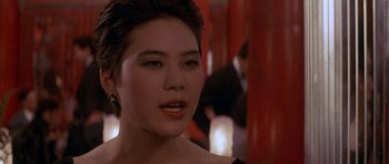 Movie still from “Year of the Dragon” (1985), directed by Michael Cimino – A person wearing a black dress; Close Up shot, Over the shoulder angle