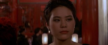 Movie still from “Year of the Dragon” (1985), directed by Michael Cimino – A woman's face in front of a group of people; Close Up shot, Over the shoulder angle