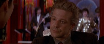 Movie still from “Year of the Dragon” (1985), directed by Michael Cimino – A person wearing a suit and tie; Close Up shot, Over the shoulder angle