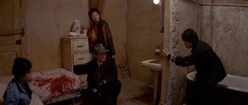 Movie still from “Year of the Dragon” (1985), directed by Michael Cimino – A man and a woman sitting in a bathroom; Wide shot, High angle