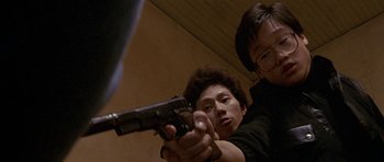 Movie still from “Year of the Dragon” (1985), directed by Michael Cimino – A man and a woman holding a gun in a room; Close Up shot, Low angle