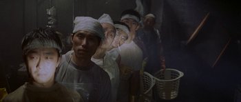 Movie still from “Year of the Dragon” (1985), directed by Michael Cimino – A group of people standing next to each other in a room; Medium shot, High angle