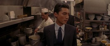 Movie still from “Year of the Dragon” (1985), directed by Michael Cimino – A man in a suit and tie standing in a kitchen; Close Up shot, Low angle