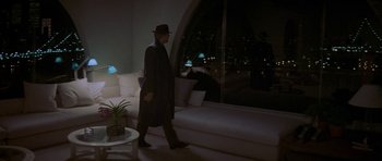 Movie still from “Year of the Dragon” (1985), directed by Michael Cimino – A man in a hat walking in a living room at night; Wide shot, High angle