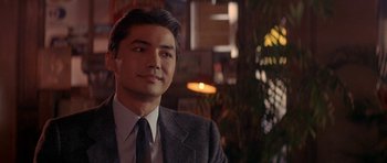 Movie still from “Year of the Dragon” (1985), directed by Michael Cimino – A person wearing a suit and tie; Close Up shot, Over the shoulder angle